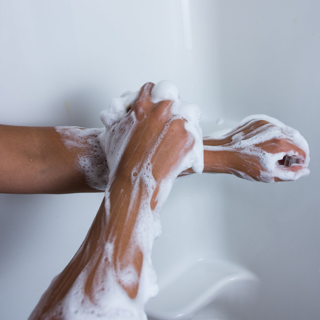 Woman washing her arms with suds from the body wash tablet in the shower. A convenient unscented soap.