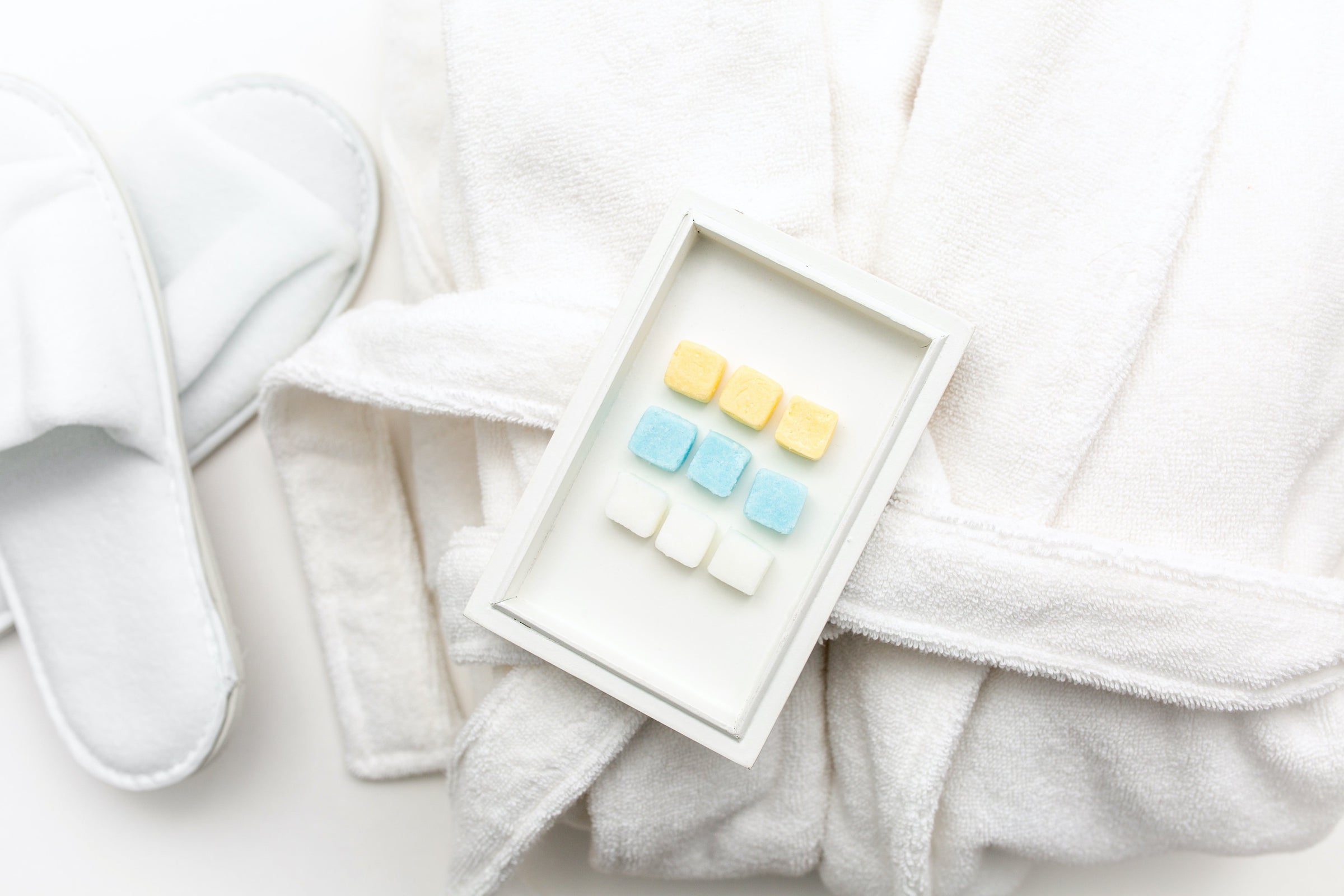Image of bathrobe, slippers and EarthSuds travel-size biodegradable tablets of shampoo, conditioner, and body wash